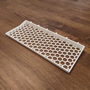 May include: White plastic tray with a honeycomb pattern. The tray is designed to hold small items.
