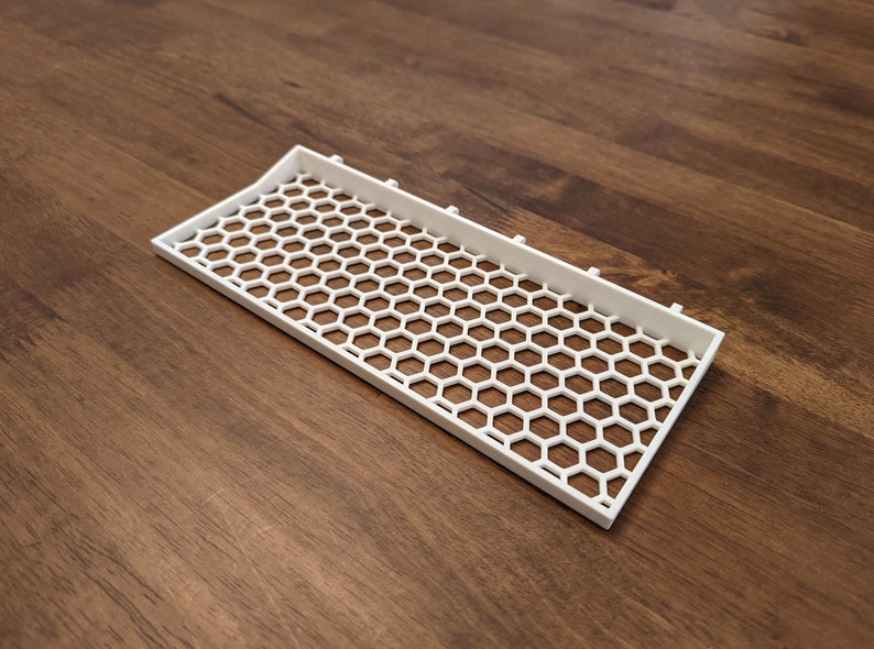 May include: White plastic tray with a honeycomb pattern. The tray is designed to hold small items.