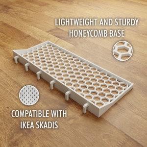 May include: White plastic shelf insert with a honeycomb design. The insert is compatible with IKEA SKADIS and is lightweight and sturdy.  "LIGHTWEIGHT AND STURDY HONEYCOMB BASE" and "COMPATIBLE WITH IKEA SKADIS" are printed on the wood surface.