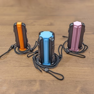 May include: Three hexagonal-shaped keychains with black, orange, and pink accents. Each keychain has a black lanyard with a black clip.