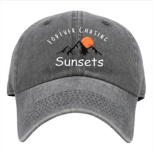 May include: A gray baseball cap with the text "Forever Chasing Sunsets" embroidered on the front. The text is white and the sun is orange.