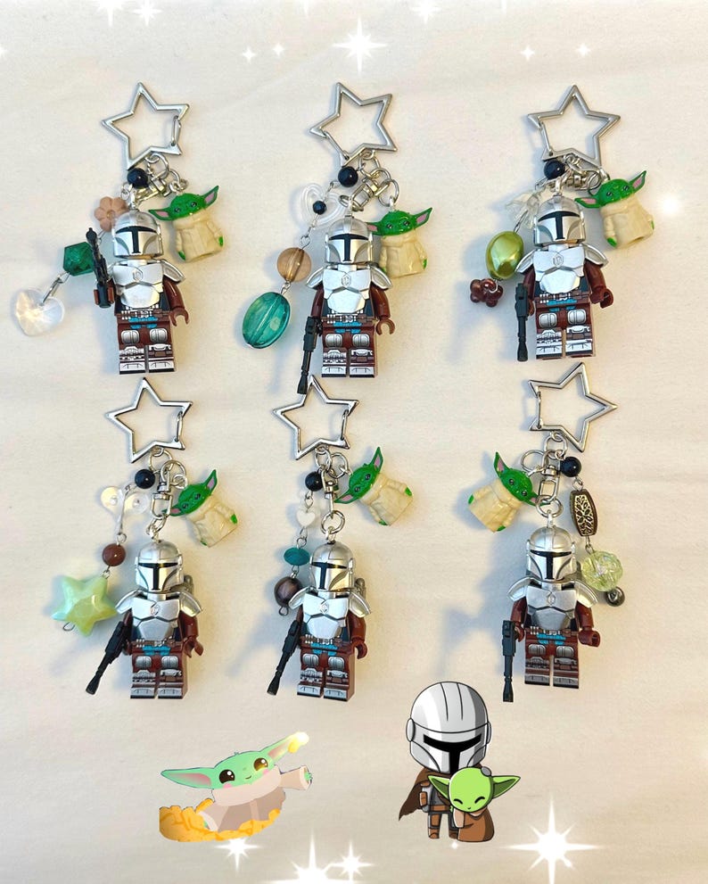 May include: Keychains featuring Mandalorian figures, each with a silver star-shaped top, a small Grogu figure, and decorative beads. The Mandalorian figures are in silver and brown armor, holding a black blaster.
