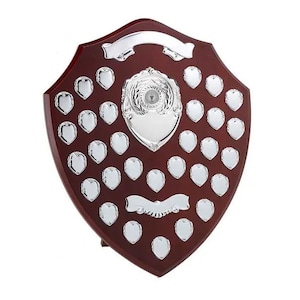 May include: A mahogany wood shield trophy with a silver centre plaque and 36 silver heart-shaped plaques for engraving names.