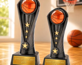 May include: Two black basketball trophies of different heights, each featuring an orange basketball at the top, three gold stars on the stem, and a gold base plate with the text BASKETBALL AWARD 2026 engraved in black lettering on the front.
