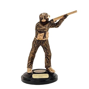 Puede incluir: Un trofeo dorado de un tirador de arcilla sosteniendo una escopeta. El trofeo está sobre una base negra con una placa dorada que dice "Your Engraving Here".
