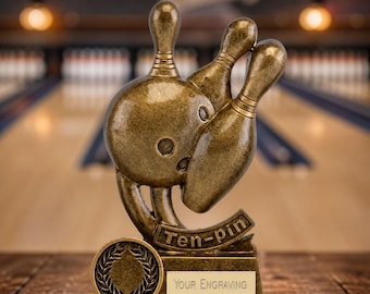 May include: A bronze-colored bowling trophy featuring a bowling ball and two pins. The trophy has a banner that reads "Ten-pin" and a space for engraving. A laurel wreath design is on the base. The background shows a bowling alley.