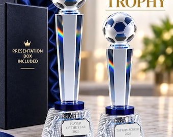 Può includere: Due trofei di calcio in cristallo con topper a forma di pallone, basi blu e targhe incise con Player of the Year 2026 e Top Goalscorer 2026. I trofei misurano 29,5 cm e 25 cm di altezza e sono presentati in una scatola blu scuro.