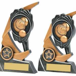 Könnte beinhalten: Zwei silberne und goldfarbene Trophäen mit einem Stern und einem kreisförmigen Design mit drei Kugeln. Die Trophäen haben einen rechteckigen Sockel mit einer leeren Plakette.