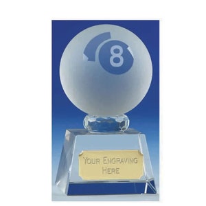Puede incluir: Un trofeo de cristal transparente con una esfera de cristal esmerilado en la parte superior. La esfera tiene un diseño de bola 8 azul. La base del trofeo tiene una placa dorada con el texto "YOUR ENGRAVING HERE".