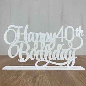 May include: White acrylic cake topper with the words "Happy 40th Birthday" in a decorative script font.