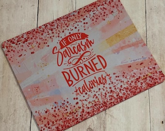 May include: A pink and white coaster with red glitter and the text "If only sarcasm burned calories".