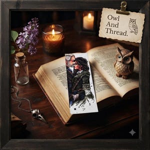 May include: A rectangular cross-stitch bookmark featuring an illustration of two figures embracing, placed on an open book. A paper tag clipped to the frame displays the text Owl And Thread. with an owl illustration, alongside a wooden owl figurine.