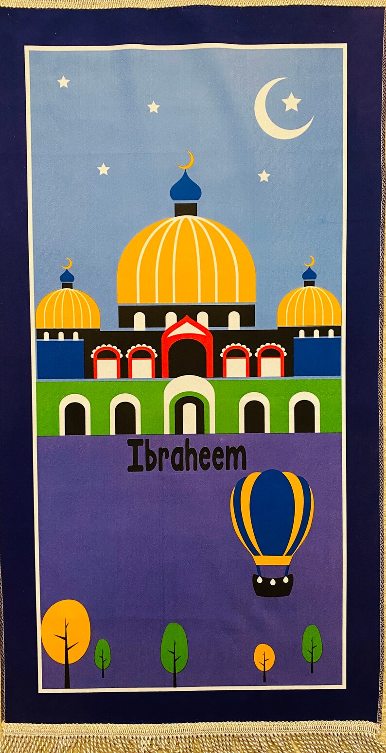 May include: A blue and purple prayer rug with a colorful illustration of a mosque with a golden dome and a hot air balloon. The rug has the name "Ibraheem" written on it.
