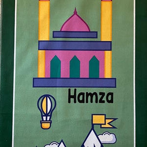 May include: A green prayer rug with a mosque, stars, mountains, a hot air balloon, and the name "Hamza" printed on it.