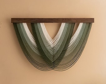 May include: A modern wall hanging featuring a dark wood top and cascading strands in shades of green and white. The strands create a layered, curved design, adding a touch of contemporary art to any space.