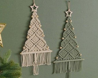 May include: Two macrame Christmas tree wall hangings, one in beige and one in green, with wooden star ornaments and wooden beads.