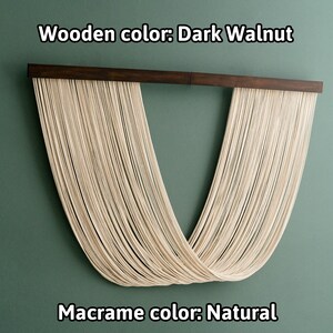 May include: A macrame wall hanging with a dark walnut wood frame. The macrame is made of natural colored cord and is shaped like a V. The text "Wooden color: Dark Walnut" and "Macrame color: Natural" is visible below the hanging.