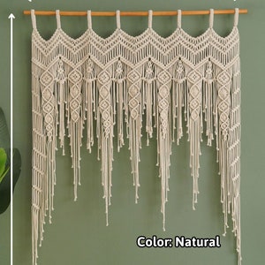 May include: A natural-colored macrame wall hanging with a scalloped top and fringe. The hanging measures 55 inches in height and 23 to 100 inches in width.