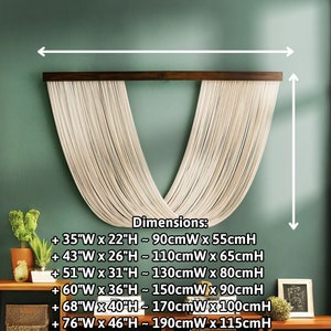 May include: A macrame wall hanging with a V-shape design in a light beige color. The hanging is made of thin cords and is attached to a dark brown wooden dowel. The wall hanging is shown against a green wall with dimensions listed in inches and centimeters.