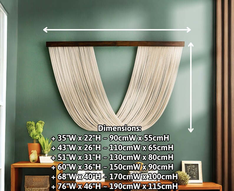 May include: A macrame wall hanging with a V-shape design in a light beige color. The hanging is made of thin cords and is attached to a dark brown wooden dowel. The wall hanging is shown against a green wall with dimensions listed in inches and centimeters.