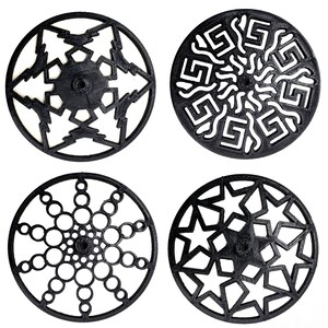 Può includere: Quattro stencil circolari in plastica nera con diversi disegni geometrici. I disegni includono un fiocco di neve, un sole con un bordo a chiave greca, un cerchio con cerchi concentrici e una stella.