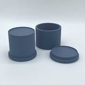 May include: A set of three grey cylindrical containers with a textured pattern. The containers are made of a smooth, matt material. The containers are ideal for storing small items, such as jewellery, coins, or other trinkets.