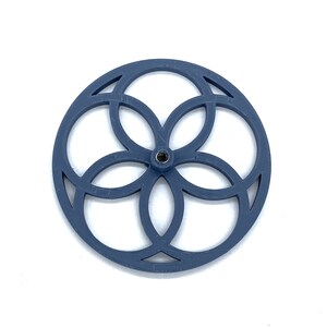 Könnte beinhalten: Ein blaues Plastikrad mit einem blumenartigen Design. Das Rad hat ein kleines Loch in der Mitte.
