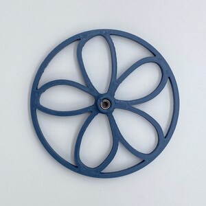 Könnte beinhalten: Ein blaues, plastikgefertigtes Rad in Form einer Blume mit sechs Blütenblättern. Das Rad hat ein kleines Loch in der Mitte.