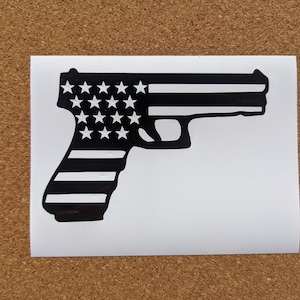 May include: Black and white silhouette of a handgun with an American flag design. The gun is outlined in black and the stars and stripes are white.