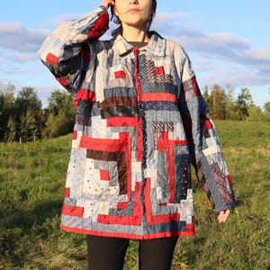 May include: A long-sleeved button-down jacket constructed from a patchwork of various fabric strips in shades of red, navy blue, light blue, and white. The garment features a collar, a front button closure, and two large rectangular patch pockets.