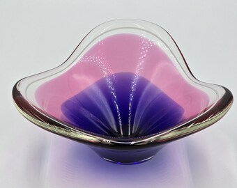 Könnte beinhalten: Eine Vintage-Glasschale mit einer einzigartigen Form und Farbgebung. Die Schale hat einen klaren Rand mit einem goldenen Rand, der in einen rosa oberen Bereich und eine tiefviolette Mitte übergeht. Das Design der Schale erinnert an eine Blume.