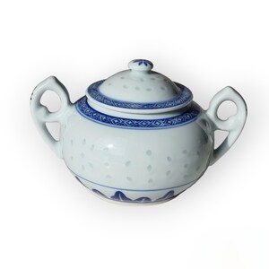 May include: A white porcelain teapot with a blue and white floral design. The teapot has a lid and two handles.