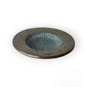 May include: A small, round, ceramic garlic crusher with a textured, green surface and a brown rim.