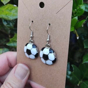 May include: A pair of silver dangle earrings with black and white soccer ball charms.