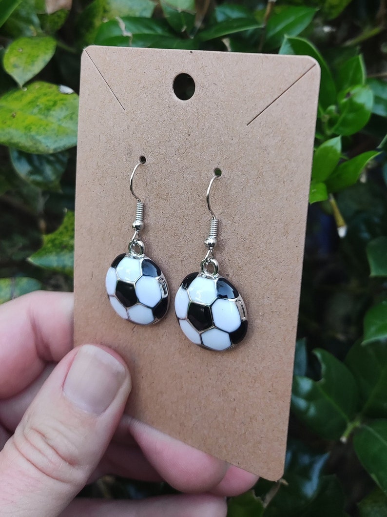 May include: A pair of silver dangle earrings with black and white soccer ball charms.