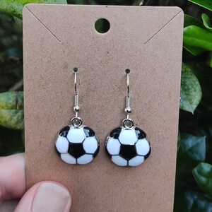 May include: A pair of silver dangle earrings with black and white soccer ball charms.
