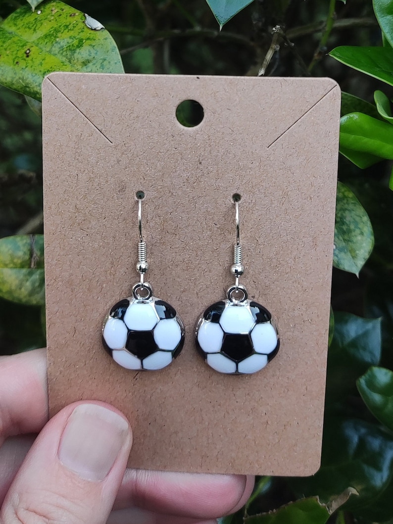 May include: A pair of silver dangle earrings with black and white soccer ball charms.