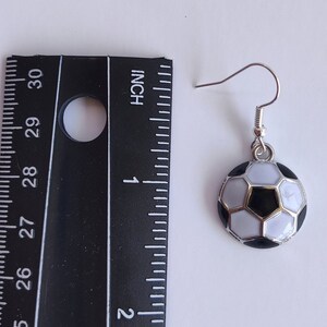 May include: Silver dangle earrings with a black and white soccer ball charm. The soccer ball is about 1 inch in diameter.