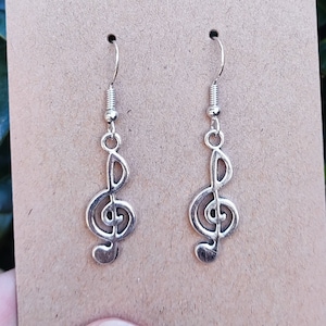 May include: A pair of silver earrings with a treble clef design.
