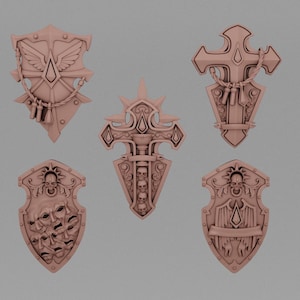 May include: A set of five light brown, monochromatic, shield-shaped decorative plaques. Each piece features intricate relief designs, including winged motifs, a cross, multiple human skulls, and various ornate scrollwork patterns.