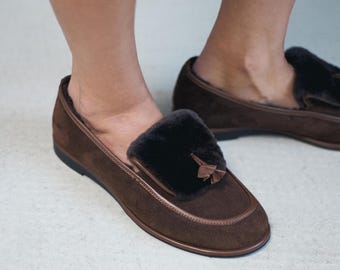 Op de afbeelding: Bruine suède loafers met een donker harig accent aan de bovenkant. De schoenen hebben een ronde neus en een klein kwastje. De zolen zijn zwart. Comfortabele schoenen.