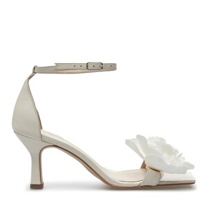 May include: White leather heeled sandals with a large white flower detail on the toe strap. The sandals have an ankle strap with a buckle closure.