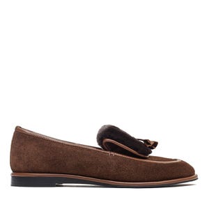 May include: A brown suede loafer with a dark brown fur accent and a small tassel. The shoe has a rounded toe and a thin, dark brown sole. The shoe is designed for comfort and style.