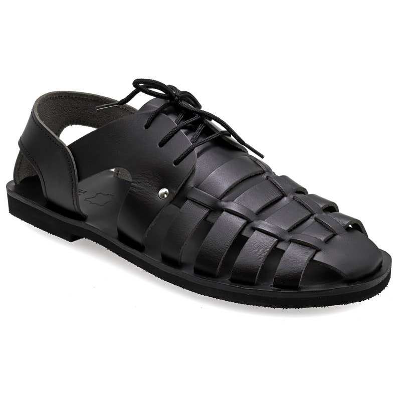 May include: Black leather sandals with a woven design on the top and lace-up closure. The sandals have a flat sole and a strap around the ankle. The footwear is designed for casual wear.
