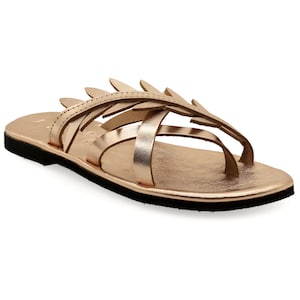 May include: Rose gold leather sandals with a leaf design and a black sole.