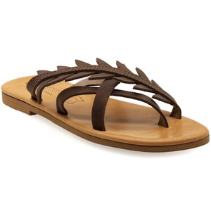 May include: Brown leather sandals with a leaf design and a flat sole.