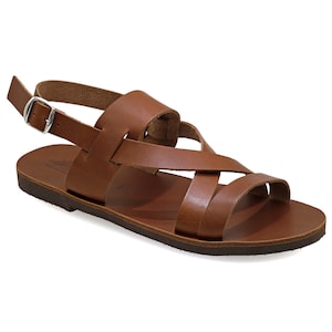 May include: Brown leather sandals with a criss-cross strap design and an adjustable ankle strap with a silver buckle.