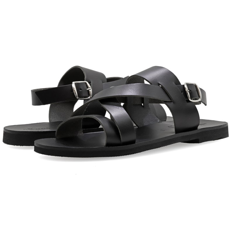 May include: Black leather sandals with a criss-cross strap design and a buckle closure.