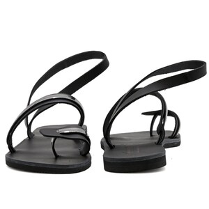 May include: Black leather sandals with a silver buckle and a strap that goes around the ankle.