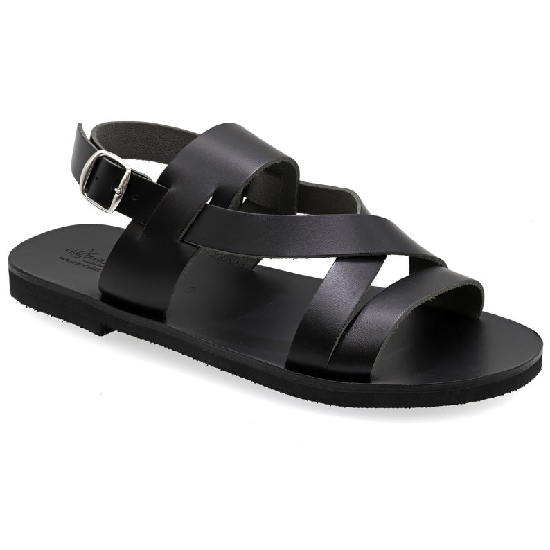 May include: Black leather sandals with a criss-cross strap design and an adjustable ankle strap with a silver buckle.